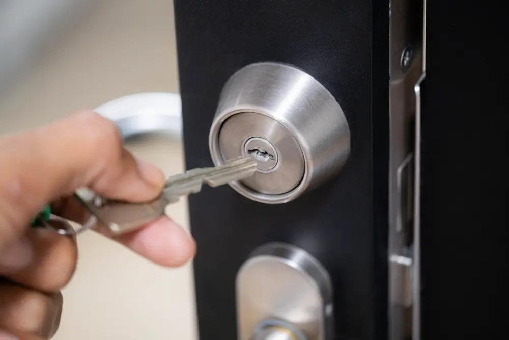 Gros plan sur une main insérant une clé dans une serrure de porte.